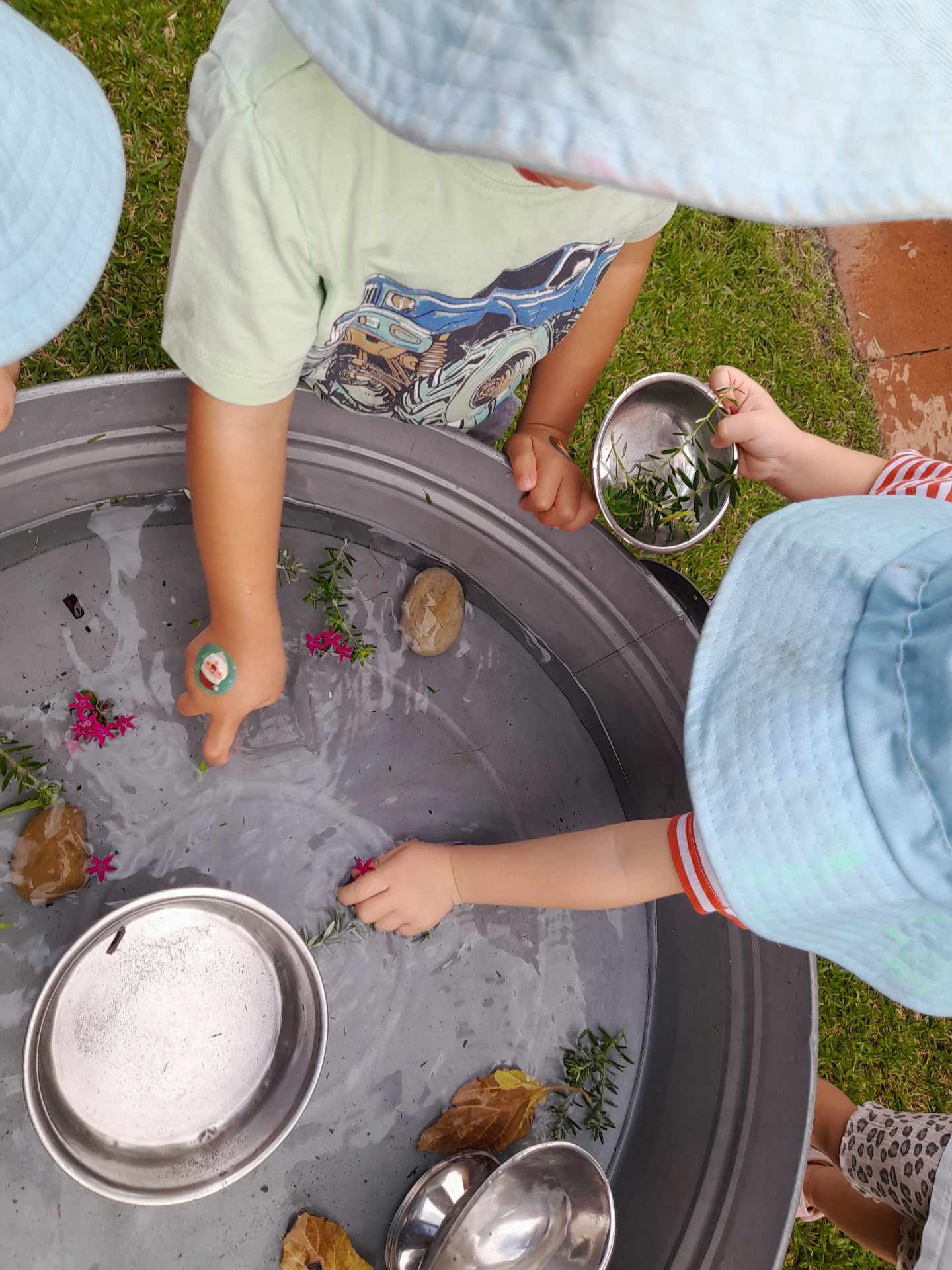Children exploring flowers, herbs and water together in a sensory play tray
