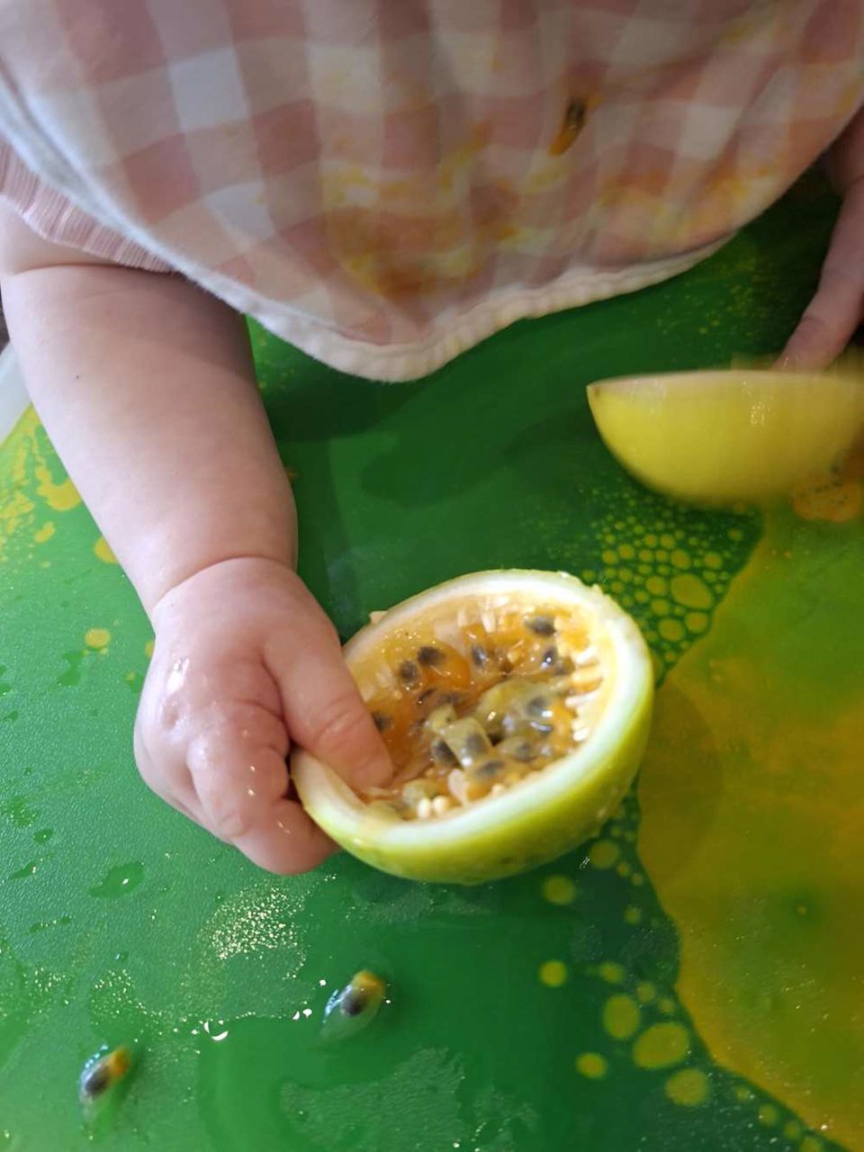 A toddler exploring passionfruit in a bright sensory play setup