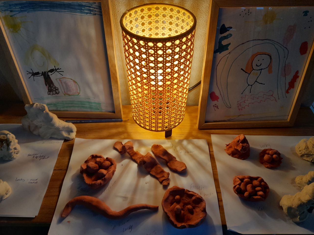 Clay creations and children's drawings displayed in a warm, softly lit learning space