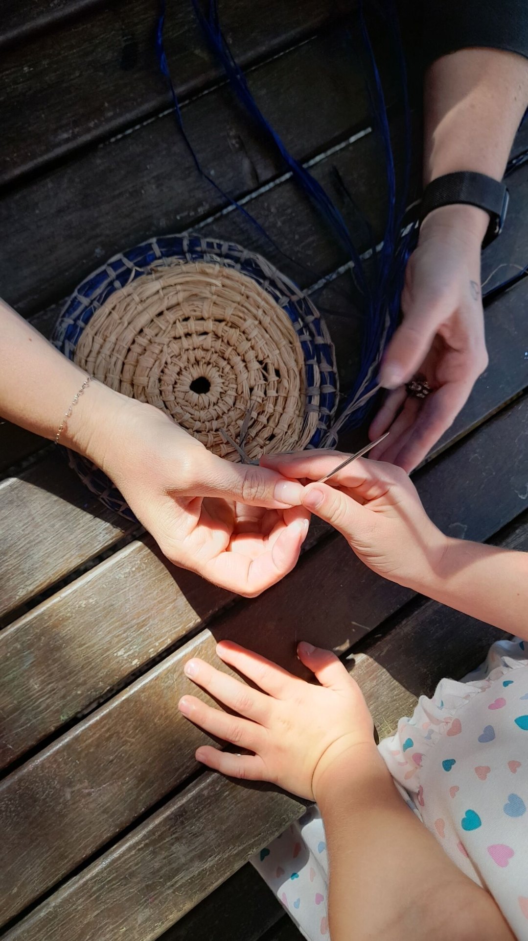 An educator guiding a child through a weaving experience with natural fibres